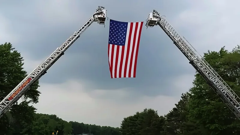 Fire engine ladders forming an arch with an American flag