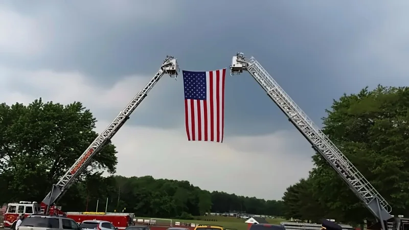 Fire engines forming a ladder arch with an American flag, ground view